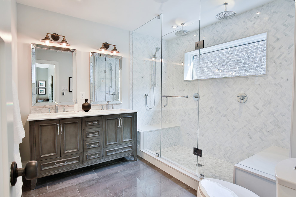 Photo of a large transitional master bathroom in Toronto with raised-panel cabinets, grey cabinets, a double shower, a one-piece toilet, gray tile, porcelain tile, white walls, porcelain floors, an undermount sink, marble benchtops and a hinged shower door.