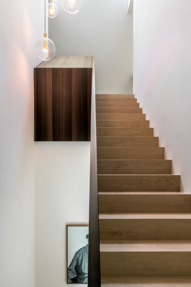 This is an example of a mid-sized modern wood u-shaped staircase in Leipzig with concrete risers and wood railing.