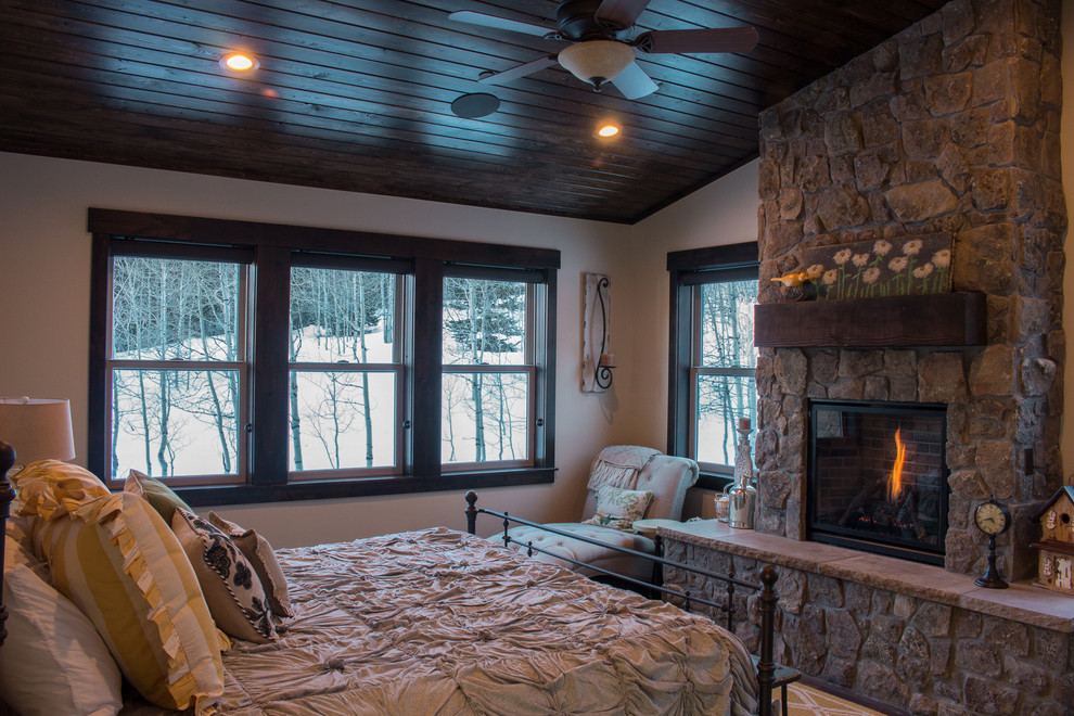This is an example of a mid-sized arts and crafts master bedroom in Salt Lake City with beige walls, dark hardwood floors, a standard fireplace and a stone fireplace surround.