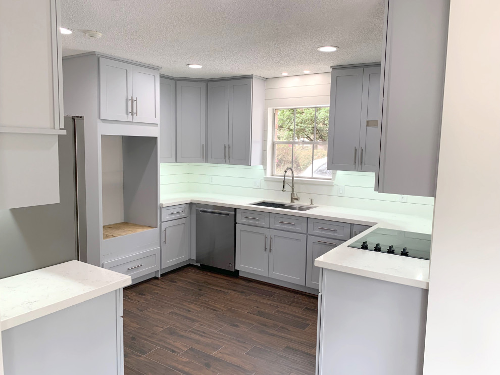 Photo of a mid-sized transitional kitchen in Houston with a single-bowl sink, shaker cabinets, grey cabinets, quartzite benchtops, white splashback, shiplap splashback, stainless steel appliances, laminate floors, brown floor and white benchtop.