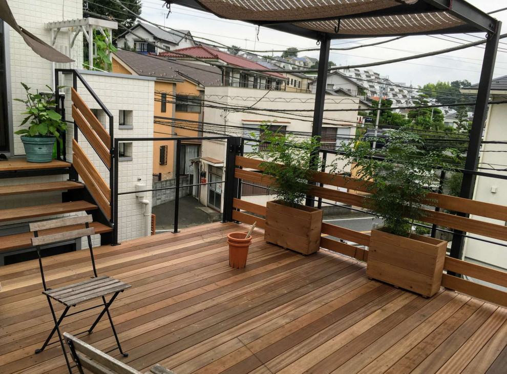 Idée de décoration pour un balcon minimaliste de taille moyenne avec des plantes en pot, un auvent et un garde-corps en matériaux mixtes.