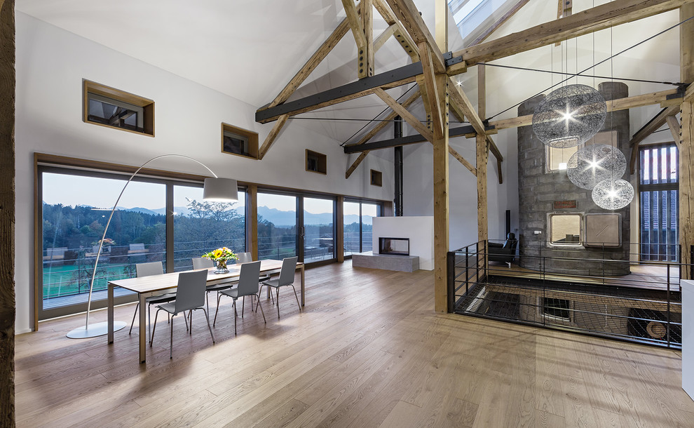 This is an example of an expansive country open plan dining in Munich with a two-sided fireplace.