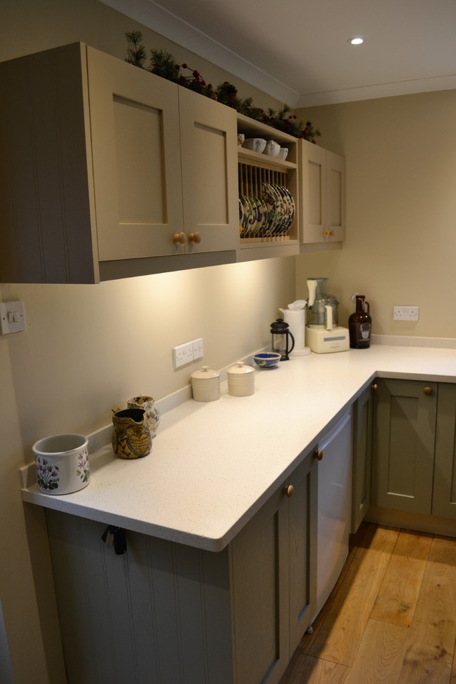This is an example of a mid-sized transitional l-shaped eat-in kitchen in Other with an integrated sink, shaker cabinets, green cabinets, solid surface benchtops, medium hardwood floors and with island.