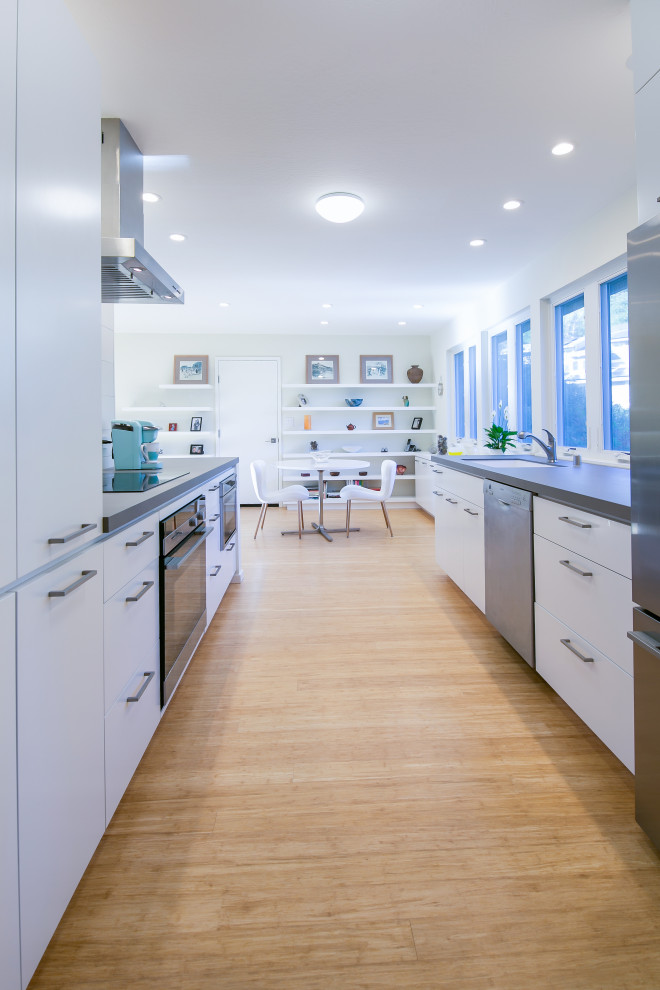 Mid-sized contemporary single-wall eat-in kitchen in San Francisco with an undermount sink, flat-panel cabinets, white cabinets, quartzite benchtops, beige splashback, porcelain splashback, stainless steel appliances, bamboo floors, a peninsula and grey benchtop.