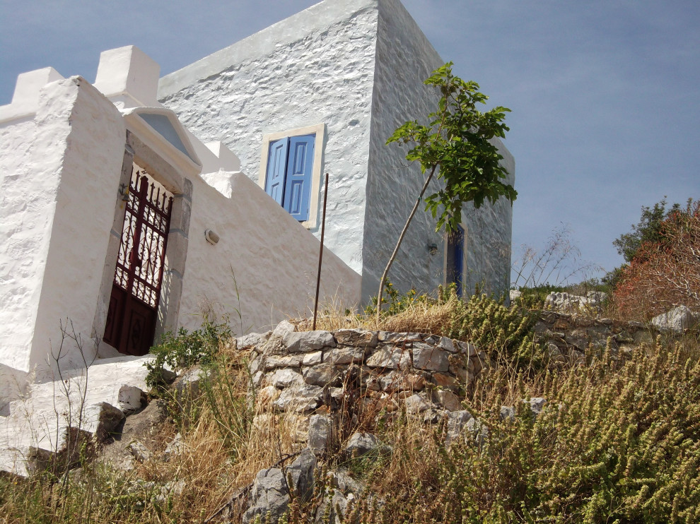Inspiration pour une petite façade de maison bleue méditerranéenne en pierre à un étage avec un toit papillon, un toit en tuile et un toit rouge.