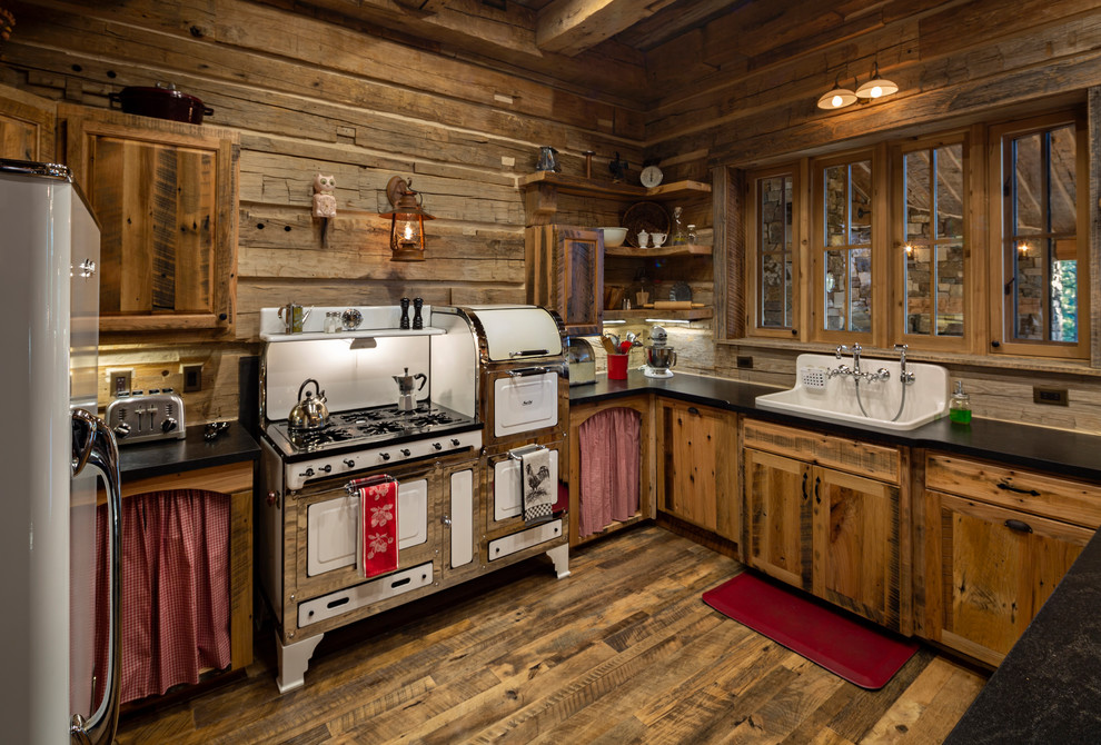 Country u-shaped kitchen in Other with a farmhouse sink, shaker cabinets, light wood cabinets, timber splashback, white appliances, dark hardwood floors, a peninsula and black benchtop.