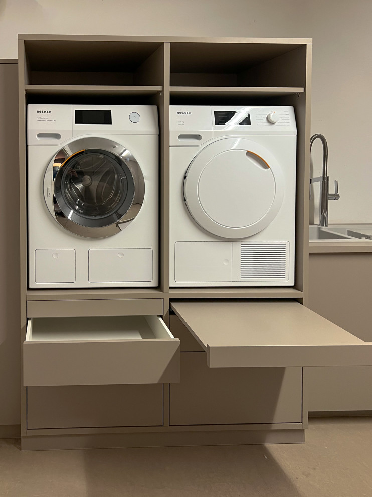 Photo of a mid-sized modern u-shaped dedicated laundry room in Cologne with a single-bowl sink, flat-panel cabinets, grey cabinets, wood benchtops, white walls, concrete floors, a side-by-side washer and dryer, beige floor and grey benchtop.