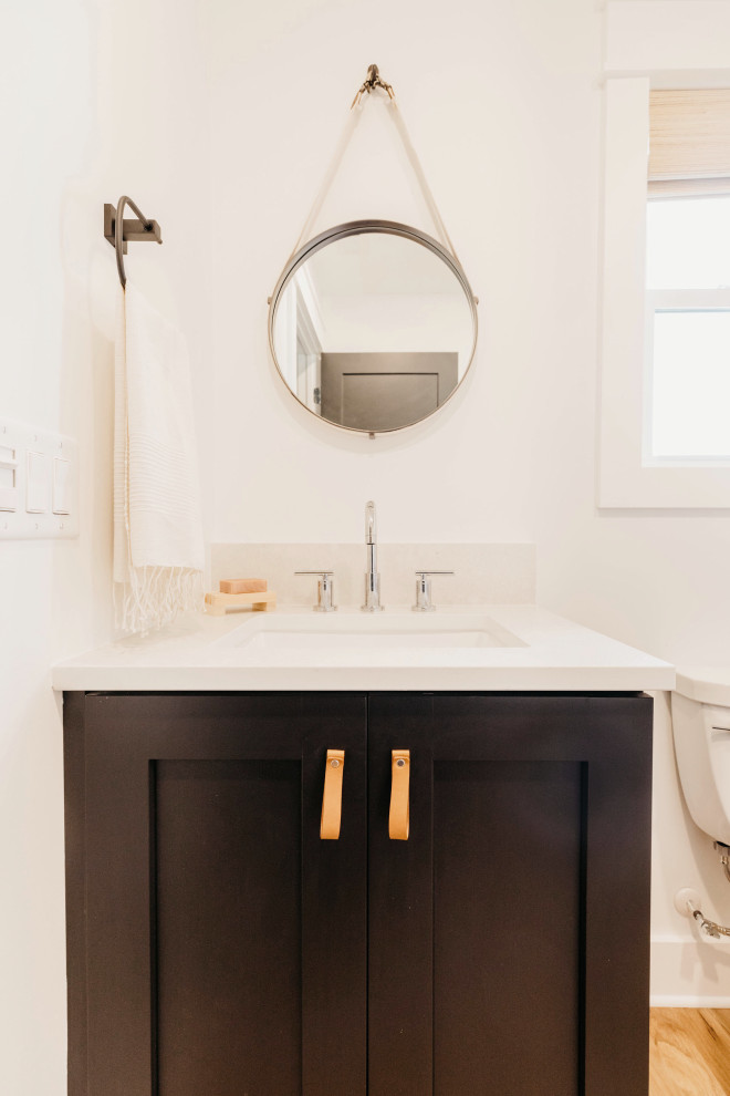 Mid-sized beach style master bathroom in San Diego with shaker cabinets, black cabinets, a two-piece toilet, white walls, medium hardwood floors, an undermount sink, engineered quartz benchtops, brown floor, white benchtops, a single vanity and a built-in vanity.