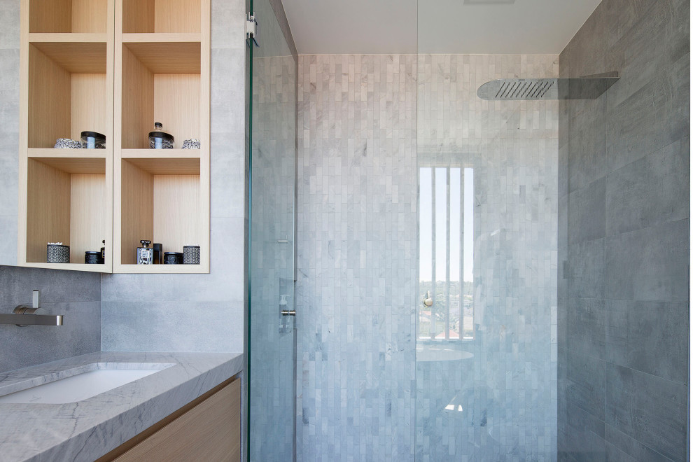 This is an example of a contemporary master bathroom in Sydney with a freestanding tub, gray tile, ceramic tile, an undermount sink, marble benchtops and grey benchtops.