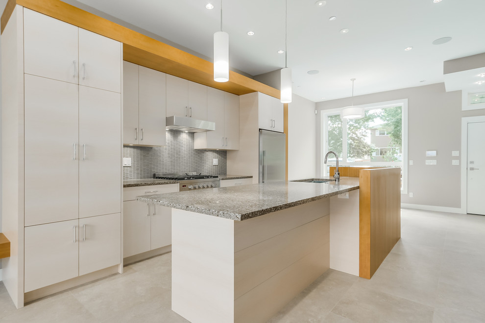 Photo of a small modern galley eat-in kitchen in Vancouver with an undermount sink, flat-panel cabinets, white cabinets, granite benchtops, grey splashback, glass tile splashback, stainless steel appliances, ceramic floors and with island.