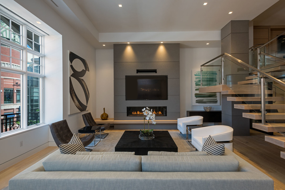 This is an example of a contemporary open concept living room in Seattle with white walls, medium hardwood floors, a ribbon fireplace, a wall-mounted tv and brown floor.