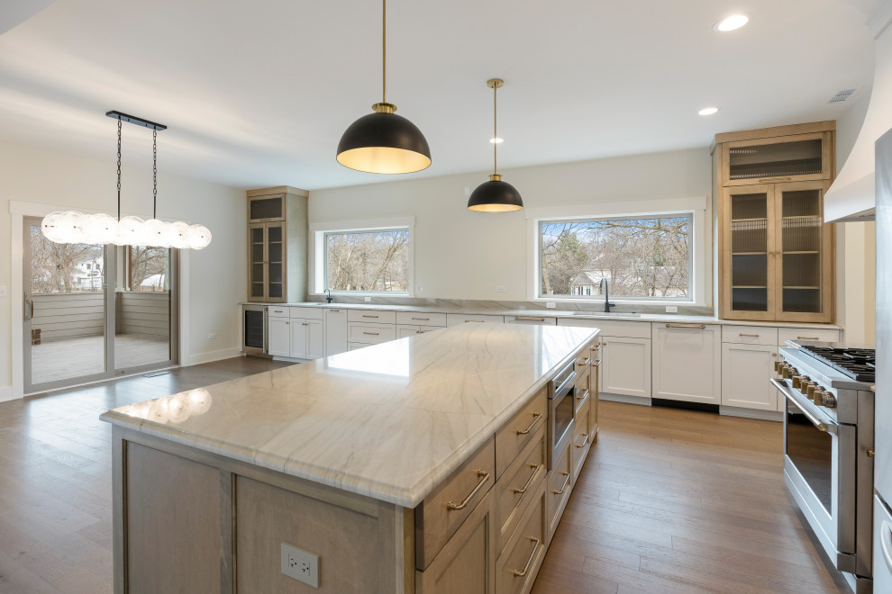 Inspiration for a huge transitional l-shaped light wood floor and brown floor eat-in kitchen remodel in Chicago with an undermount sink, shaker cabinets, white cabinets, quartz countertops, white backsplash, quartz backsplash, stainless steel appliances, an island and white countertops