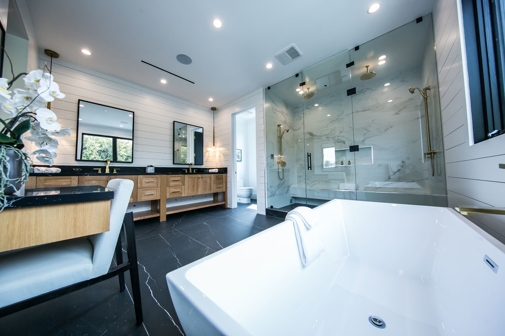 Inspiration for a large modern master white tile and wood-look tile marble floor, black floor, double-sink, tray ceiling and wood wall bathroom remodel in Los Angeles with raised-panel cabinets, light wood cabinets, white walls, an integrated sink, marble countertops, a hinged shower door, black countertops and a built-in vanity