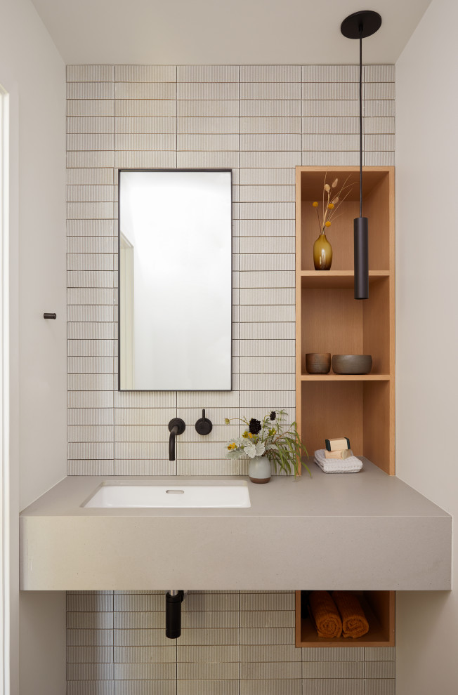 Photo of a small modern cloakroom in San Francisco with open cabinets, a one-piece toilet, white tiles, ceramic tiles, white walls, porcelain flooring, a submerged sink, engineered stone worktops, beige floors, grey worktops and a floating vanity unit.