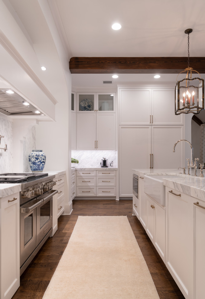 Inspiration for a large traditional l-shaped separate kitchen in Dallas with a farmhouse sink, shaker cabinets, white cabinets, marble benchtops, white splashback, marble splashback, panelled appliances, medium hardwood floors, with island, white benchtop and exposed beam.