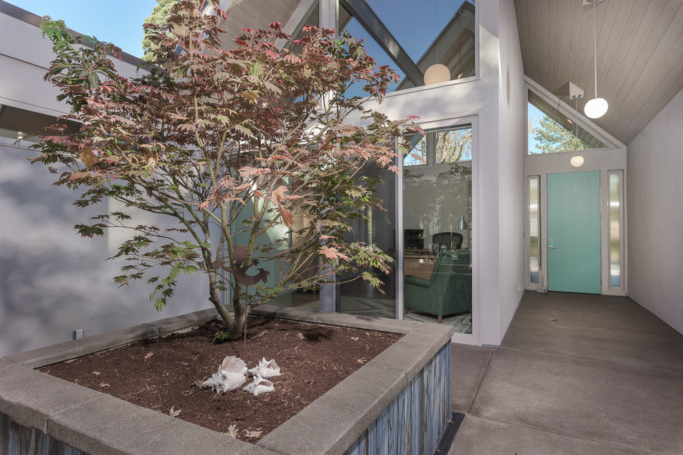 This is an example of a large midcentury one-storey stucco grey house exterior in Portland with a gable roof and a shingle roof.