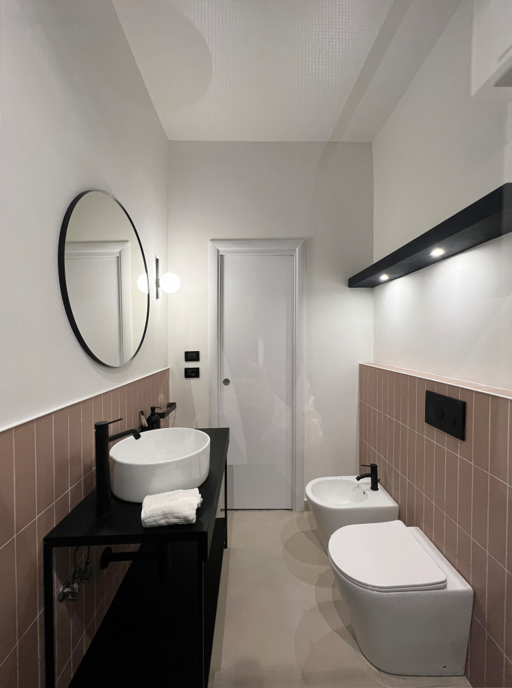 Foto på ett litet funkis svart badrum med dusch, med öppna hyllor, svarta skåp, en kantlös dusch, en toalettstol med separat cisternkåpa, rosa kakel, keramikplattor, vita väggar, klinkergolv i porslin, ett fristående handfat, träbänkskiva, vitt golv och med dusch som är öppen