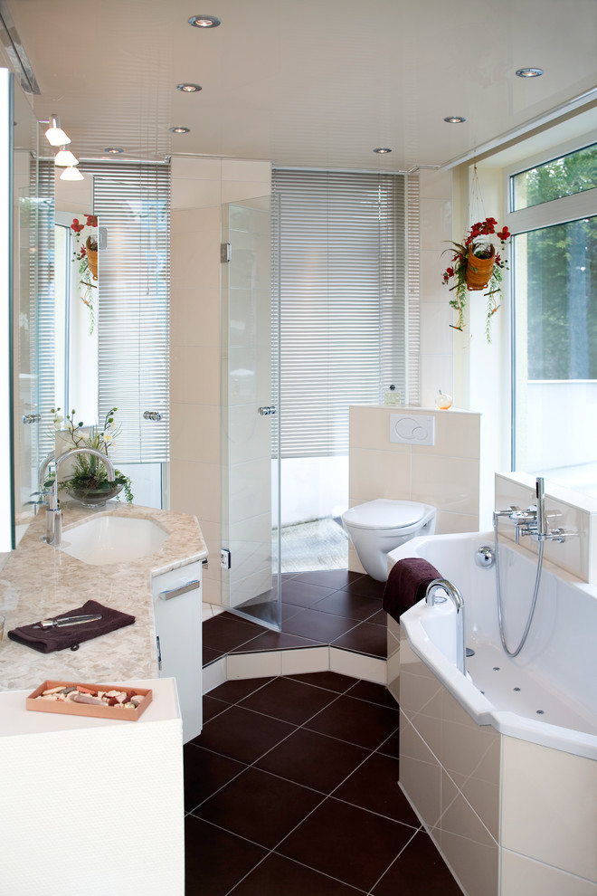 Small mediterranean bathroom in Frankfurt with flat-panel cabinets, white cabinets, a drop-in tub, a curbless shower, a two-piece toilet, white tile, white walls, an integrated sink, solid surface benchtops, brown floor and a sliding shower screen.