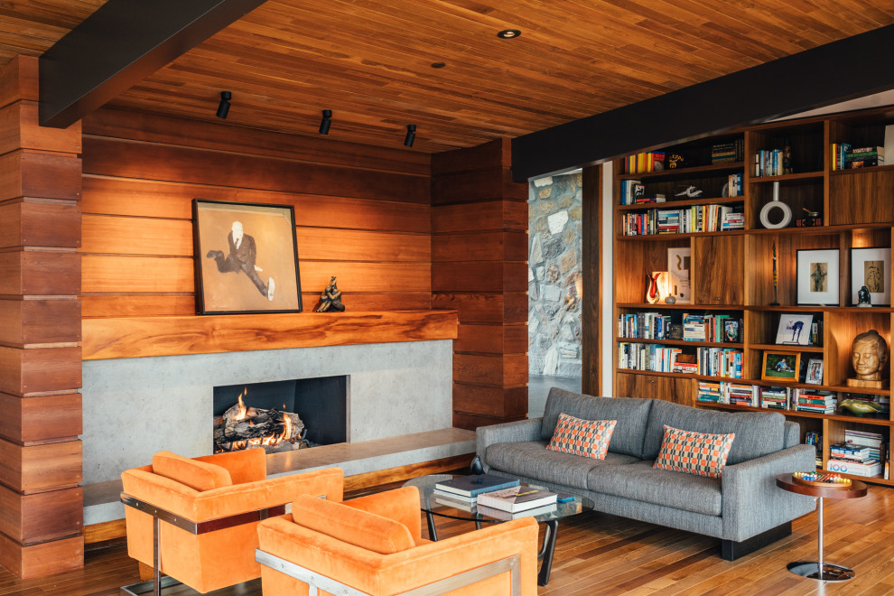 Design ideas for a midcentury family room in San Diego with a library, medium hardwood floors, a ribbon fireplace, a concrete fireplace surround, no tv, exposed beam, wood and wood walls.