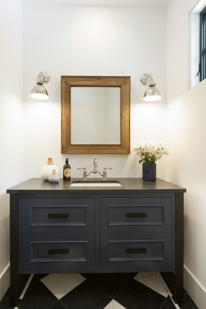 This is an example of a transitional powder room in Minneapolis with recessed-panel cabinets, blue cabinets, black and white tile, white walls, an undermount sink, multi-coloured floor and grey benchtops.
