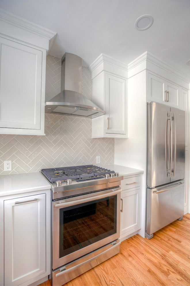 Inspiration for a small transitional l-shaped medium tone wood floor kitchen pantry remodel in New York with an undermount sink, shaker cabinets, white cabinets, quartzite countertops, gray backsplash, subway tile backsplash, stainless steel appliances, an island and white countertops