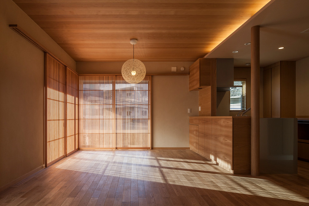 This is an example of an asian living room in Tokyo with beige walls and light hardwood floors.