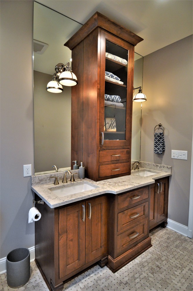 Photo of a large transitional master bathroom in Milwaukee with glass-front cabinets, medium wood cabinets, an alcove tub, a shower/bathtub combo, a two-piece toilet, beige tile, ceramic tile, beige walls, ceramic floors, a drop-in sink, laminate benchtops, grey floor and a hinged shower door.