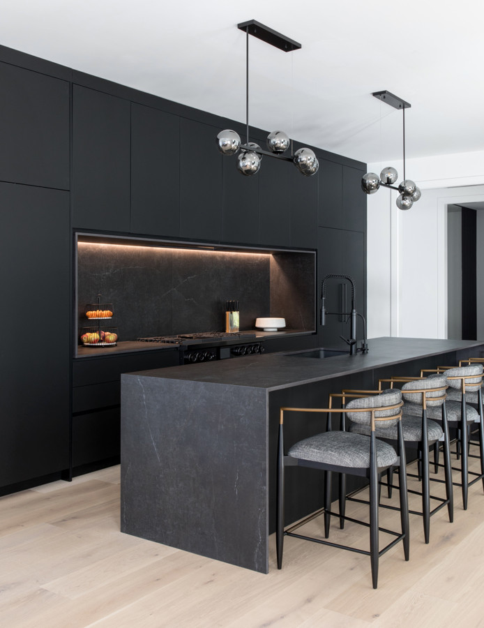 Esempio di una grande cucina minimalista con lavello sottopiano, ante lisce, ante nere, paraspruzzi nero, elettrodomestici neri, parquet chiaro e top nero