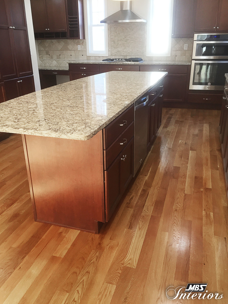 Inspiration for a large transitional medium tone wood floor eat-in kitchen remodel in Cincinnati with an undermount sink, recessed-panel cabinets, dark wood cabinets, quartz countertops, beige backsplash, stone tile backsplash, stainless steel appliances and an island