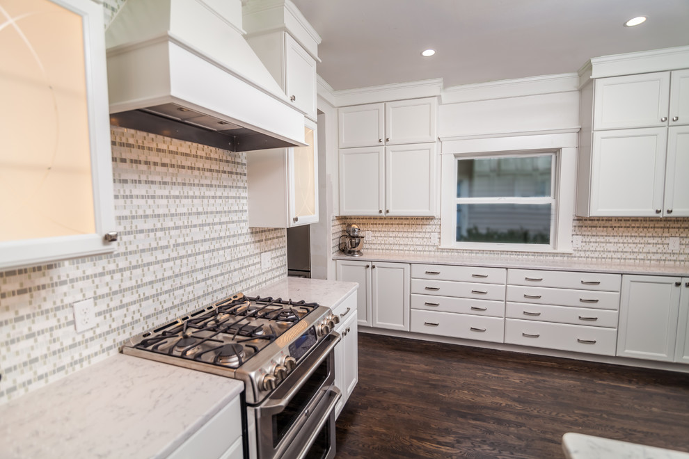 Photo of a mid-sized transitional u-shaped separate kitchen in Boise with a farmhouse sink, recessed-panel cabinets, white cabinets, quartzite benchtops, multi-coloured splashback, mosaic tile splashback, stainless steel appliances, dark hardwood floors, no island and brown floor.