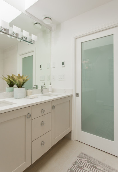 Inspiration for a mid-sized contemporary master bathroom in Vancouver with recessed-panel cabinets, grey cabinets, a freestanding tub, a corner shower, a one-piece toilet, white tile, porcelain tile, white walls, pebble tile floors, an undermount sink and engineered quartz benchtops.