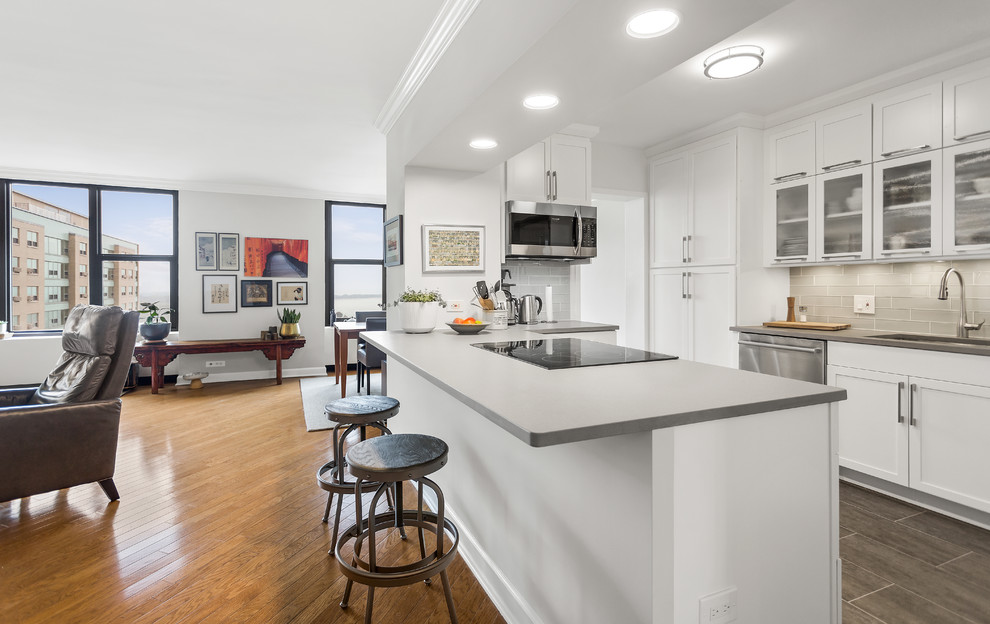Photo of a contemporary u-shaped kitchen in Chicago with an undermount sink, shaker cabinets, white cabinets, a peninsula, grey floor and grey benchtop.