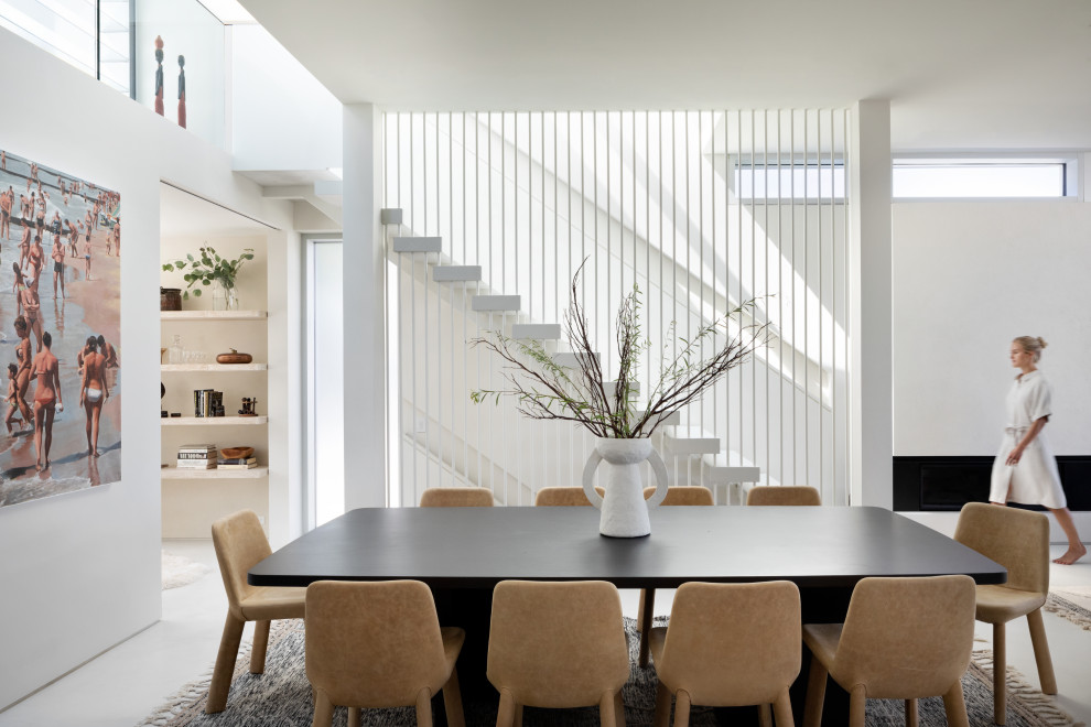 Réalisation d'une salle à manger design de taille moyenne avec un mur blanc, sol en béton ciré, une cheminée standard, un manteau de cheminée en béton et un sol gris.