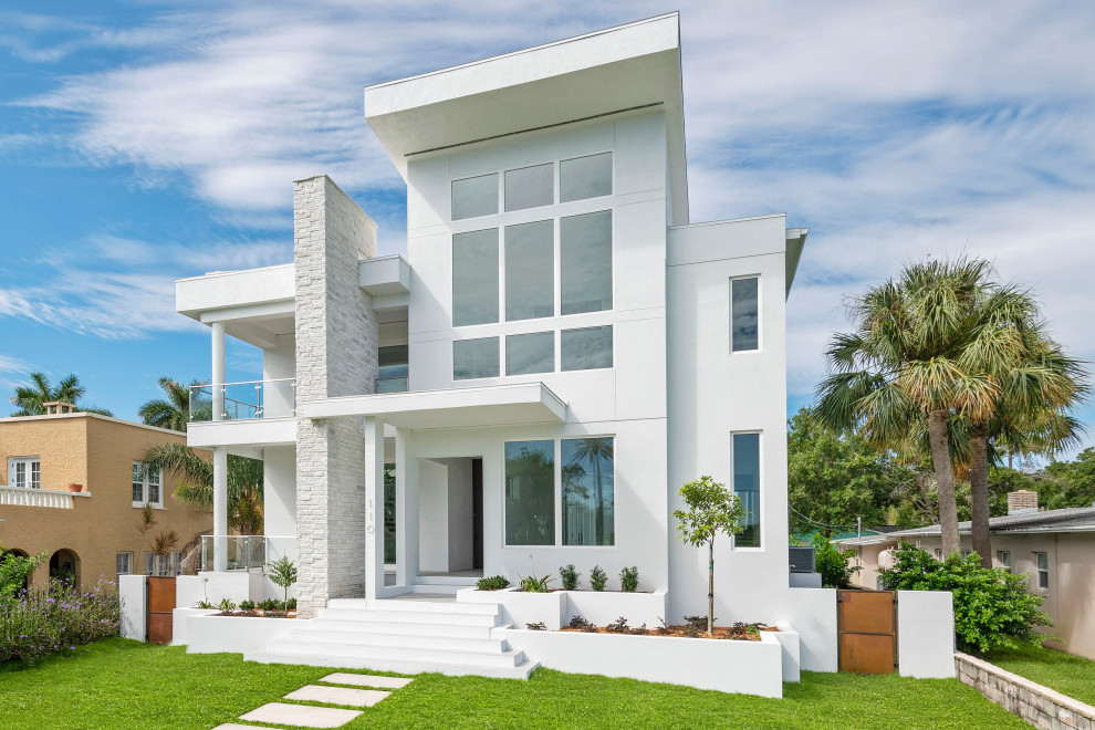 This is an example of a large contemporary two-storey stucco white house exterior in Other with a flat roof.