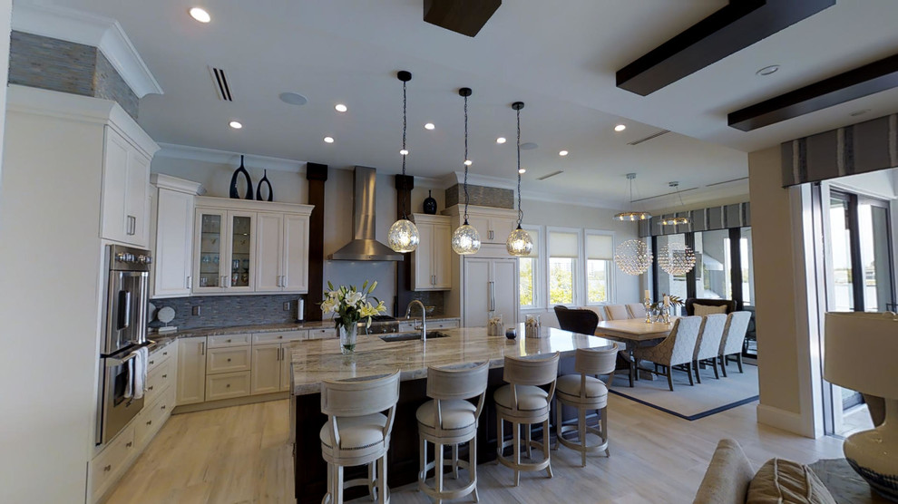 Inspiration for a large transitional l-shaped ceramic tile and beige floor open concept kitchen remodel with a farmhouse sink, recessed-panel cabinets, white cabinets, granite countertops, blue backsplash, glass tile backsplash, stainless steel appliances and an island