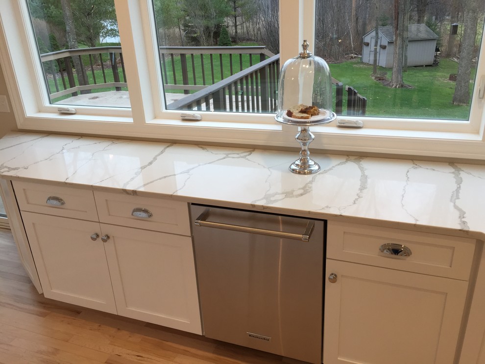 Inspiration for a contemporary light wood floor kitchen remodel with an undermount sink, shaker cabinets, white cabinets, quartz countertops, stainless steel appliances and an island