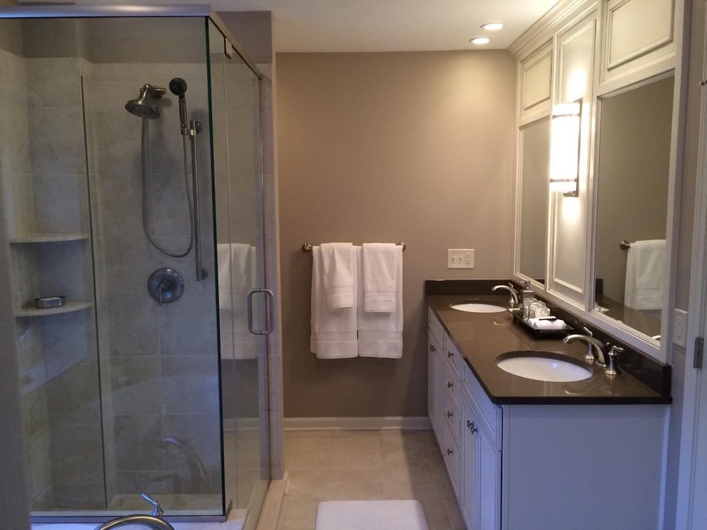 This is an example of a mid-sized traditional master bathroom in Cleveland with an undermount sink, raised-panel cabinets, white cabinets, engineered quartz benchtops, a drop-in tub, a two-piece toilet, beige tile, porcelain tile, beige walls and porcelain floors.