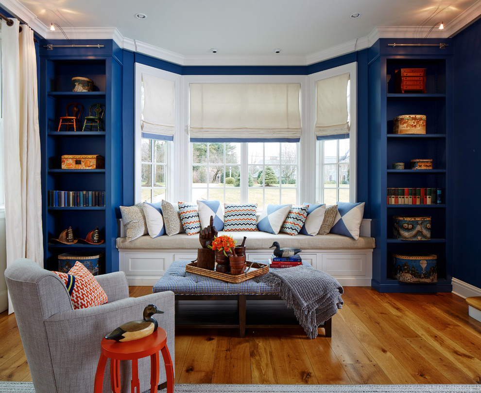 Design ideas for a mid-sized traditional enclosed living room in New York with a library, blue walls, medium hardwood floors, a standard fireplace, a brick fireplace surround, no tv and brown floor.