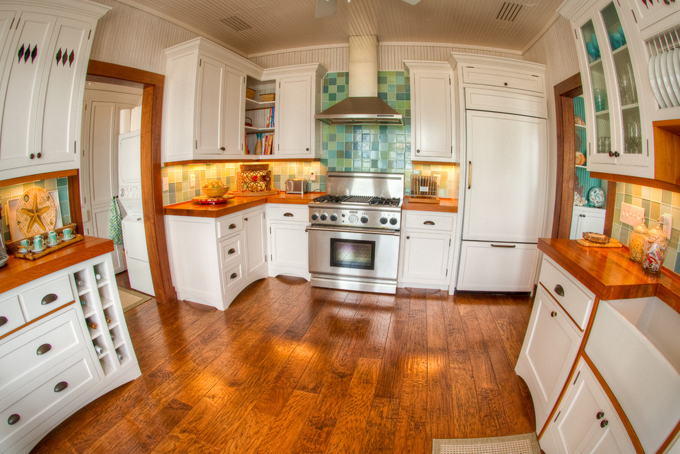 Inspiration for a mid-sized tropical galley dark wood floor and brown floor eat-in kitchen remodel in Other with a farmhouse sink, shaker cabinets, white cabinets, wood countertops, green backsplash, glass tile backsplash, stainless steel appliances and no island