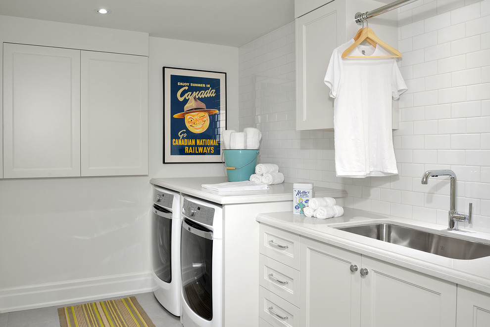 Photo of a large traditional galley dedicated laundry room in Toronto with an undermount sink, recessed-panel cabinets, white cabinets, quartz benchtops, white walls, ceramic floors, a side-by-side washer and dryer and white benchtop.