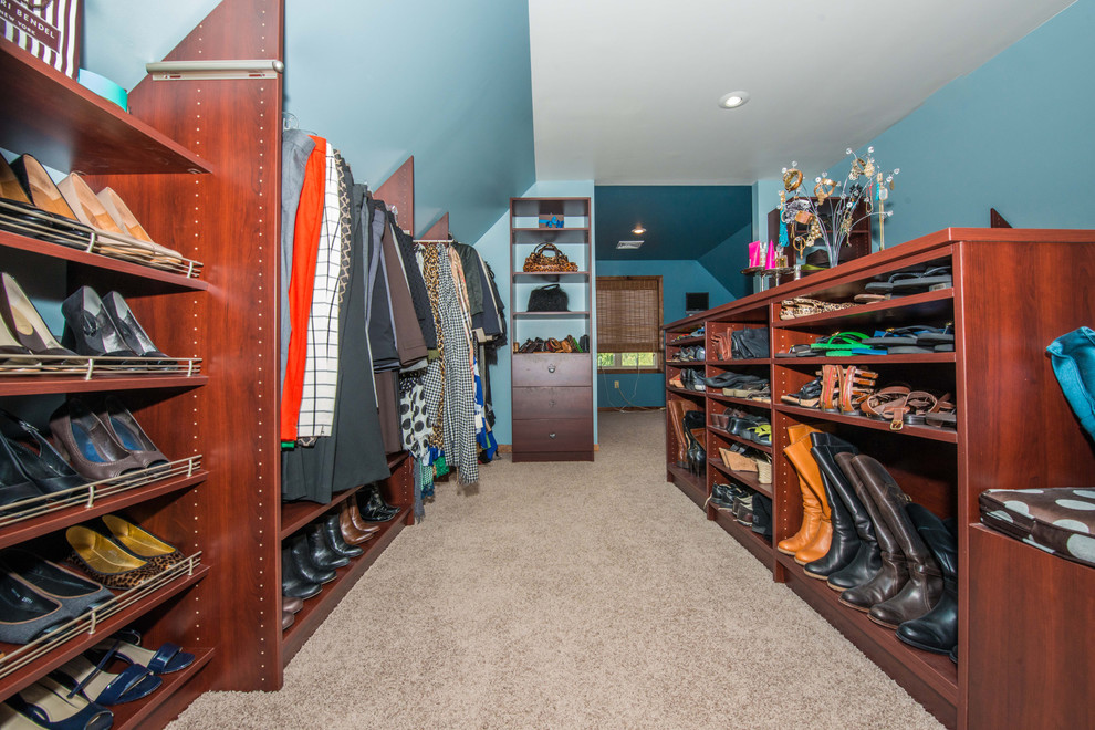 This is an example of a large traditional gender-neutral walk-in wardrobe in Philadelphia with open cabinets, brown cabinets, carpet and beige floor.