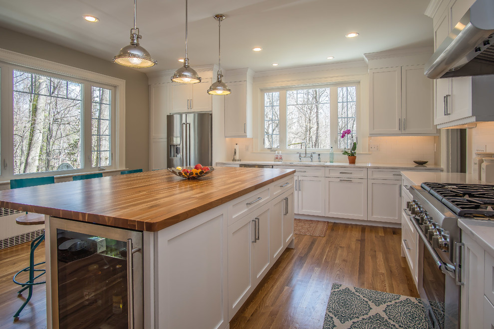 This is an example of a large country l-shaped eat-in kitchen in Bridgeport with an undermount sink, shaker cabinets, white cabinets, quartz benchtops, white splashback, subway tile splashback, stainless steel appliances, medium hardwood floors, with island and green floor.