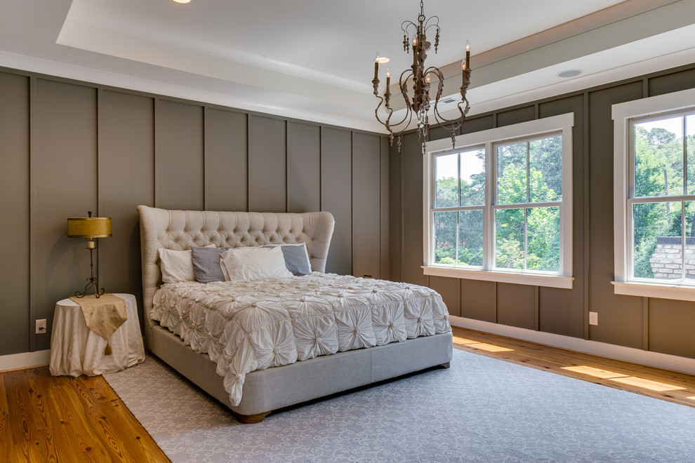 Large country master bedroom in Charlotte with brown walls and light hardwood floors.