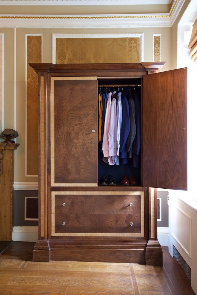 Photo of a traditional men's dressing room in London with flat-panel cabinets and dark wood cabinets.
