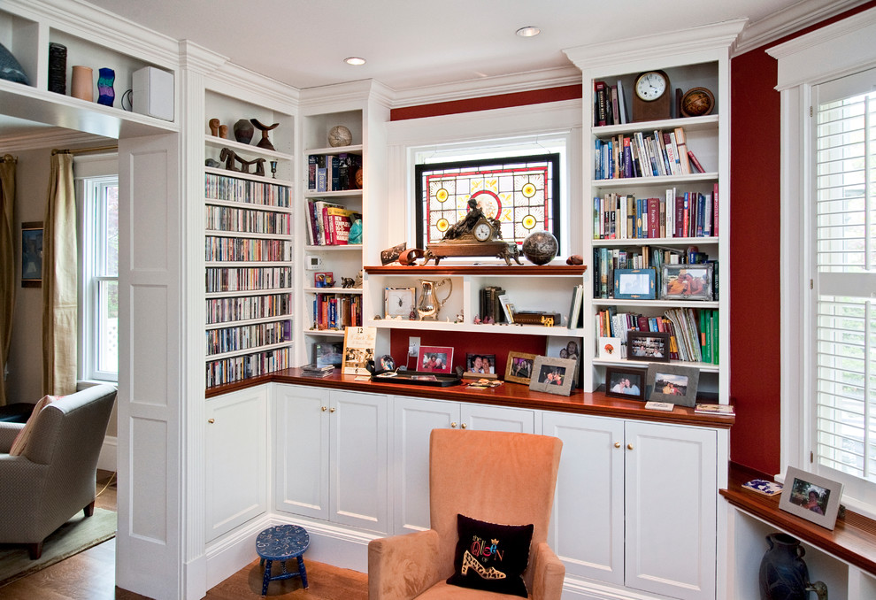 This is an example of a mid-sized traditional living room in Boston with a library and red walls.