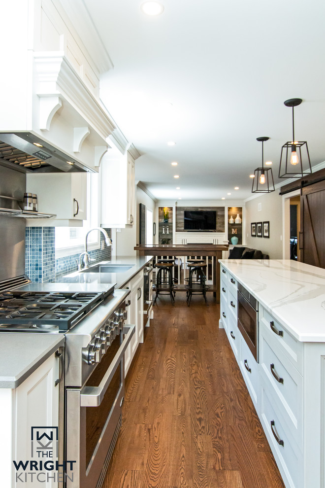 Inspiration for a large transitional medium tone wood floor and brown floor kitchen remodel in Toronto with an undermount sink, shaker cabinets, white cabinets, wood countertops, blue backsplash, mosaic tile backsplash, stainless steel appliances, an island and white countertops