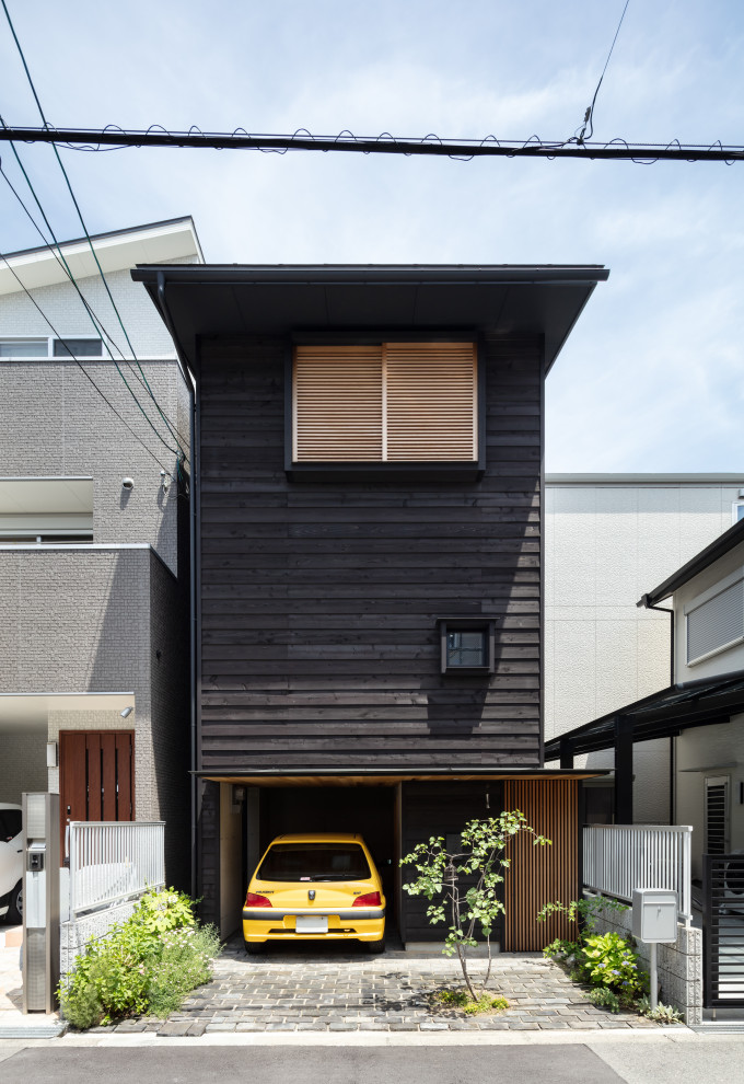 This is an example of a small and black detached house in Osaka with three floors, wood cladding, a pitched roof, a metal roof, a grey roof and shiplap cladding.