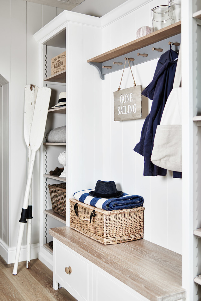 Inspiration for a beach style mudroom in Wiltshire with light hardwood floors, beige floor and white walls.