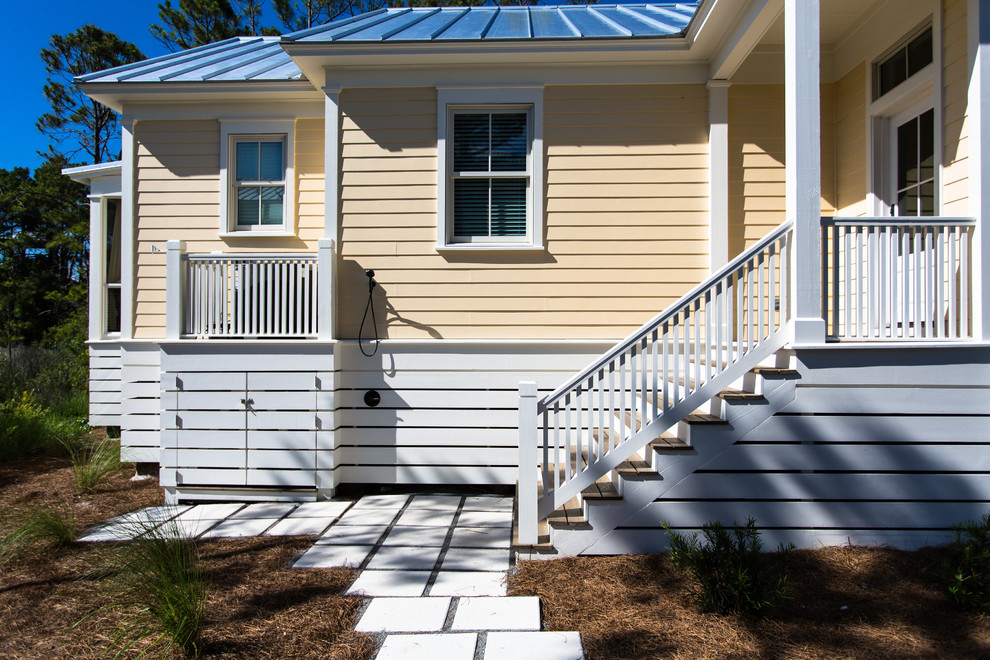 This is an example of a mid-sized traditional one-storey yellow exterior in Miami with vinyl siding and a gable roof.