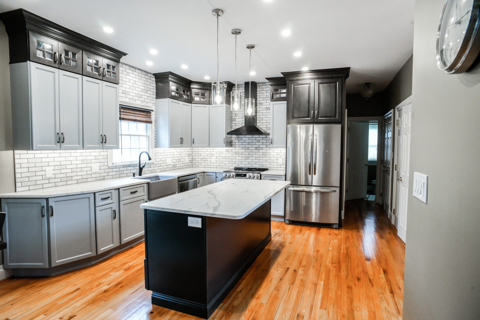 Inspiration for a transitional light wood floor and orange floor kitchen remodel in Philadelphia with raised-panel cabinets, gray cabinets, quartz countertops, mosaic tile backsplash, an island and white countertops